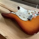 Elektrická kytara s trupem v barevném přechodu od žluté po tmavě hnědou (sunburst) a bílým pickguardem. Nástroj má tři snímače typu single-coil, tři…