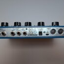 Zadní strana modrého efektového pedálu s kovovým panelem a pěti černými oválnými knoflíky. Na panelu jsou nápisy INPUT MONO STEREO, OUTPUT MONO STERE…