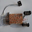 Fotografie zobrazuje ručně vyrobený elektronický efekt v provedení na perforovaném desce s viditelnými pájky a zapojenými součástkami. Zařízení obsah…