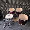 Vícedílná bicí souprava v tmavě červeném metalickém provedení s chromovaným kováním. Na blanách tomů a basového bubnu je viditelné logo „Gretsch“, na…
