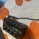 Černý sluchátkový zesilovač s nápisem behringer a Ultra-Compact 4-Channel Stereo Headphone Amplifier HA400. Zařízení má čtyři výstupní konektory pro…