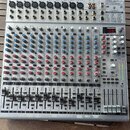 Stříbrný mixážní pult s nápisem EUROBACK UR244FX-PRO. Zařízení obsahuje několik vstupních kanálů s modrými a červenými otočnými knoflíky, posuvníky h…