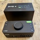 Černý audio rozhraní s velkým centrálním ovladačem a několika tlačítky. Na zařízení jsou nápisy „evo 4“, „EVO AUDIENT“ a označení tlačítek „48V“, „1“…
