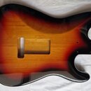 Tělo elektrické kytary v tvaru Stratocaster s lakem v přechodu od žluté přes červenou k černé (sunburst). Povrch je vysoce lesklý a bez viditelných p…