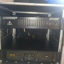 Otevřený transportní case s dvěma černými rackovými zesilovači. Horní zařízení nese nápisy EUROPOWER, BEHRINGER a EP1500 PROFESSIONAL SOUND REINFORCE…