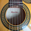 Detail znuzové kytary zaměřený na otvor rezonanční skříně s ozdobnou rozetou. Uvnitř je vidět štítek s nápisy „Alhambra“, „Made in Spain“ a „Since 19…