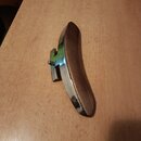 Na fotografii je zobrazen kovový a dřevěný předmět, pravděpodobně opěrka na violinčel nebo kontrabas. Předmět má zakřivený tvar s kovovým povrchem a…