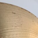 Detailní záběr na povrch mosazného činely s viditelným broušením. Na povrchu je vyražen nápis AVEDIS ZILDJIAN CO, pod kterým následuje text GENUINE T…
