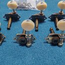 Šest kusů ladících mechanismů s bílými, kulatými knoflíky. Kovové části jsou v mosazném a stříbrném provedení. Na mechanismech nejsou žádné viditelné…