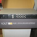 Zadní strana šedé audio rozhraní s černým panelem konektorů. Na zařízení jsou vidět nápisy Power In 100-240VAC 50/60Hz 30W, USB, MIC, OPTICAL OUTPUTS…