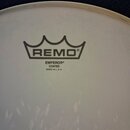 Detail bílého, matného bicího koženu. Uprostřed je černé logo REMO v podobě koruny a pod ním nápisy EMPEROR®, COATED a MADE IN U. S. A. V dolní části…
