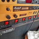 Sada rackových zařízení značky Marshall v zlatém provedení. Jsou zde viditelné modely VALVE MIDI PRE-AMP JMP-1, SIGNAL PROCESSOR JFX-1 a STEREO VALVE…