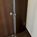 Stříbrný kovový mikrofonní stojan s trojnožkou. Horní část je zakončena černým držákem. Na stojanu nejsou vidět žádné značky ani nápisy. Povrch vykaz…