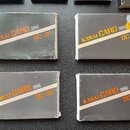 Čtyři černé obdélníkové krabičky s oranžovými a bílými nápisy. Na každé je uveden text KAWAI CARD RAM a označení DC-32. Povrchy krabiček vykazují zná…