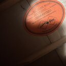 Oválná papírová nálepka oranžové barvy s černým textem. Obsahuje nápisy Model 1957 SG-200 Reissue, Number 25071500851 a GUARANTEED for its quality an…