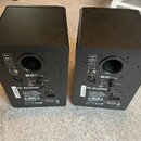 Dva černé studiové monitory značky M-AUDIO, model BX5 D3. Na zadní stranách jsou viditelné vstupy TRS a XLR, ovládací prvky pro volume a akustické na…