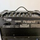 Zadní strana černého kytarového komba značky Roland. Na horní části jsou umístěny ovládací knoflíky a nápisy FOOT SW, RECORDING OUT/PHONES. Na stříbr…
