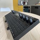 Černý MIDI kontrolér s mřížkou čtvercových padů a několika otočnými knoflíky. Na spodní hraně jsou viditelné nápisy EDIT, GLOBAL, POLYRHYTHM a CLEAR.…