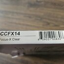 Detail bílého papírového obalu s černými nápisy a čárovým kódem. Je zde uveden kód CCFX14 a název Focus-X Clear. Čárový kód obsahuje čísla 6 59007 00…