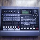 Šedý digitální vícemístní nahrávací studio s černým ovládacím panelem. Na přístroji je nápis Roland DIGITAL STUDIO WORKSTATION VS-840 a logo EZ EDITO…