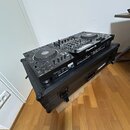 Černý DJ set osazený dvěma přehrávači a mixážním pultem, umístěný v transportním kufru s kovými hranami. Na mixážním pultu je viditelné logo Pioneer…