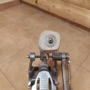 Fotografie zachycuje kovový basový pedál z pohledu shora. Na plošince je vidět nápis „TAMA“ a pod ním menší text „IRON COBRA“. Beater je vyroben z bí…
