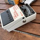 Bílý kytarový ladič s černým spínacím pedálem. Na přístroji jsou nápisy BOSS, Chromatic Tuner TU-3, OUTPUT, BYPASS a INPUT. V horní části je displej…