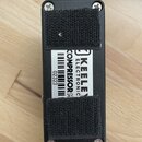 Spodní strana černého kytarového efektu s dvěma pásky suchého zipu. Na bílém štítku je uveden nápis KEELEY ELECTRONIC COMPRESSORM a čárový kód s čísl…