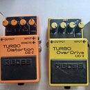 Dvě efektové pedály značky BOSS v oranžovém a žlutém provedení. Oranžový pedál nese nápisy TURBO Distortion a DS-2, žlutý pedál nápisy TURBO Over Dri…