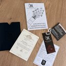 Fotografie zobrazuje doprovodné dokumenty k hudebnímu nástroji rozložené na dřevěném povrchu. Je zde uživatelský manuál s nápisem „Mayones Guitars &…