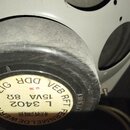 Černý cylindrický transformátor s bílou papírovou nálepkou na spodní straně. Na nálepce je uveden text: VEB RFT, DDR LEIPZIG, L 3402, 15VA 8Ω a FERNM…