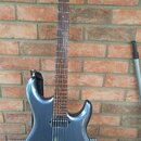Modře metallic elektrická kytara s hnědým hmatníkem a dřevěnou hlavou. Na hlavě je svisle napsaný nápis Ibanez. Kytara má jeden humbucker u kobylky,…