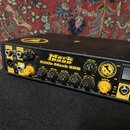 Černý basový zesilovač s žlutými detaily a ovládacími prvky. Na předním panelu je nápis Markbass Little Mark 58R a logo Markbass. Zařízení obsahuje n…