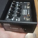 Černý efekt pedál v originální krabici s nápisem MXR BASS INNOVATIONS bass d.i.+. Na zařízení jsou vidět ovládací knoflíky, přepínače a nápisy CLEAN…