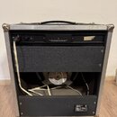 Zadní strana kytarového komba v hliníkovém flightcase s černým potahem a rukojetí. V horní části je napájecí kabel, pojistka s nápisem T 0.5A a štíte…