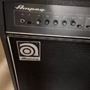 Černý basový kombozesilovač značky Ampeg. Ovládací panel obsahuje vstup INPUT, tlačítko PAD a potenciometry s popisky GAIN, BASS, ULTRA MID, TREBLE,…