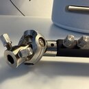 Detailní pohled na kovový spojovací mechanismus stavu, pravděpodobně součást stojanu. Součásti jsou vyrobeny z anodizovaného hliníku v stříbrné barvě…