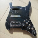 Černý plastový pickguard pro elektrickou kytaru s třмя snímači. Horní dva jsou humbuckery s chromovaným krytem, spodní je singl v průhledném plastové…
