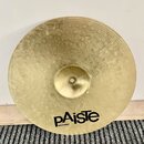 Zlatavý kovový činel s jemným rýhováním a hámrnutými důlky v horní části. Na spodní straně je černý nápis pAiste a pod ním menší text MADE IN GERMANY…