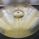 Kovový činel v zlatavé barvě s viditelným kovánívým povrchem. Na povrchu je nápis „Paiste“ a níže označení „Full Crash 18"“. Činel je položen na čern…