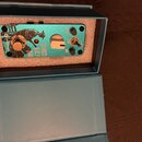 Modrý efekt pedál v originální krabičce s pěnovou výplní. Na pedálu je zobrazen nápis „GLAMED QUIET MAN“ a logo „Vintage“. Zařízení má jeden stomeč,…