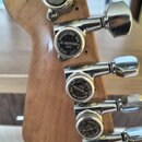 Detailní záběr na hриф kytary s chromovanými ladicími kolíky. Na hlavách kolíků je vidět nápis MAGNUM LOCK-TRAP, logo GOTOH a slova JAPAN, RELEASE, L…