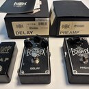 Tři černé kytarové efekty v kovovém provedení s texturovaným spodkem. První pedál má nápisy ERNIE BALL a TAP, prostřední nápisy ECHOPLEX a DELAY s ov…
