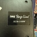 Detail černého plastového povrchu zařízení s nalepeným štítkem. Na štítku je bílé logo img v rámečku, nápis Stage Line® a modelové označení ECM-310W.…