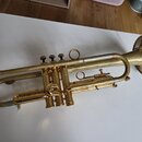 Zlatá trumpeta s mosazným povrchem. Na korýtku je vyryt nápis „CORNET BY JAMES BRAND“. Nástroj vykazuje známky opotřebení v podobě drobných škrábanců…