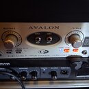 Stříbrný rackový přístroj s nápisem AVALON. Na předním panelu jsou dva otočné knoflíky s popisky BOOST a TONE, vstupy INPUT a THRU, výstup OUT a přep…