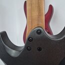 Detail zadní strany kytary v místě spoje krku s tělem. Tělo je v matné černé barvě a krk je vyroben z přírodního světlého dřeva s viditelnou struktur…