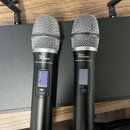 Dvě černé bezdrátové rukávní mikrofony s kovovými mřížkami. Na obou je vidět logo „the Lct.bone“ a nápis „free solo HT 590 MHz“. Mikrofony mají v těl…