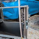 Fotografie zachycuje detail hliníkového transportního kufru s černým vnitřním povrchem. U pravého boku je přiloženo krejčovské metr, který ukazuje vý…