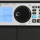 Detail ovládacího panelu elektronického hudebního zařízení s modrým LCD displejem a velkým černým otočným ovladačem. Na displeji je nápis Studio REVE…